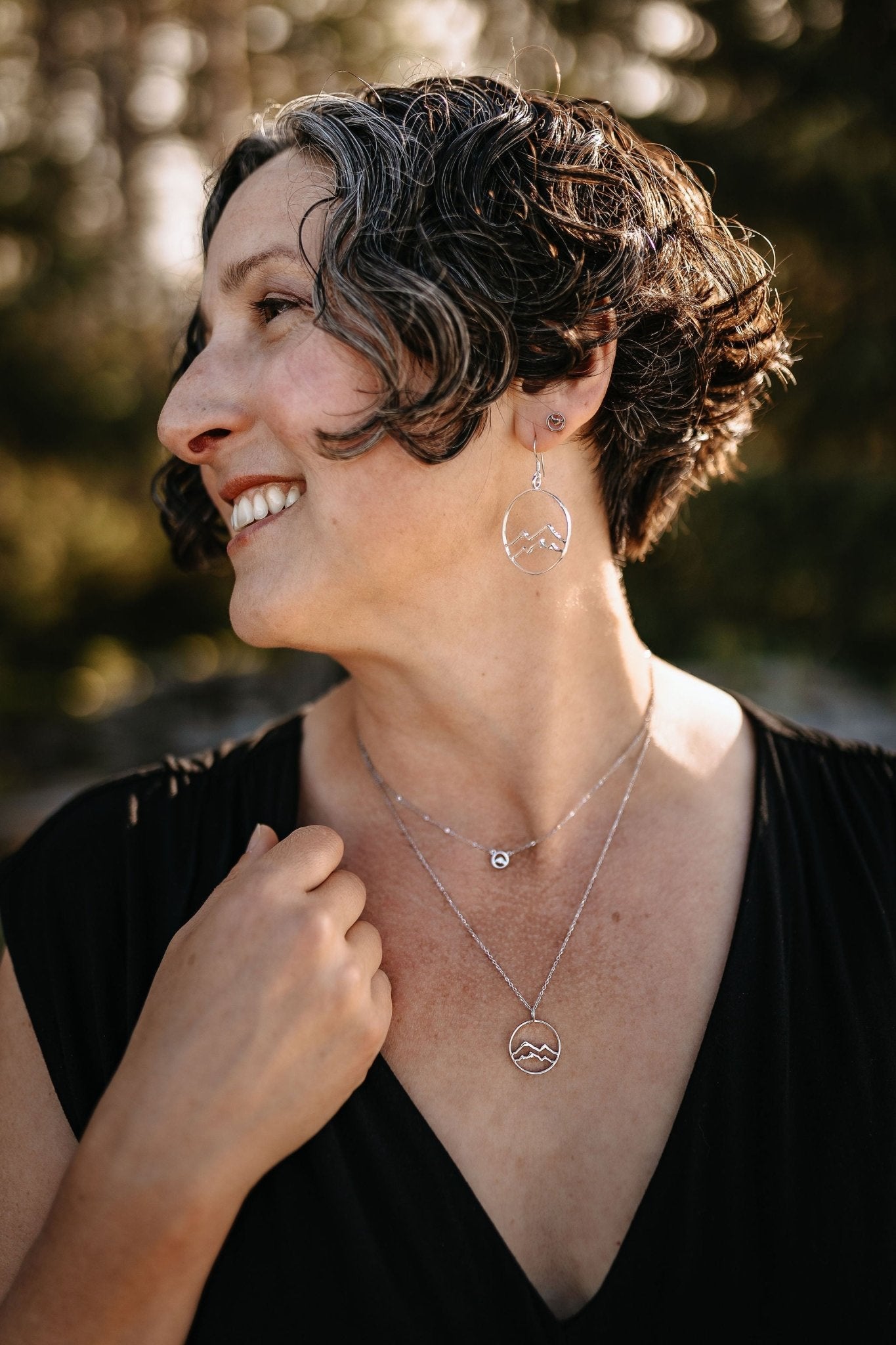 model wearing sterling silver coast mountain jewelry set with mountain circle earrings and layered silver mountain necklaces