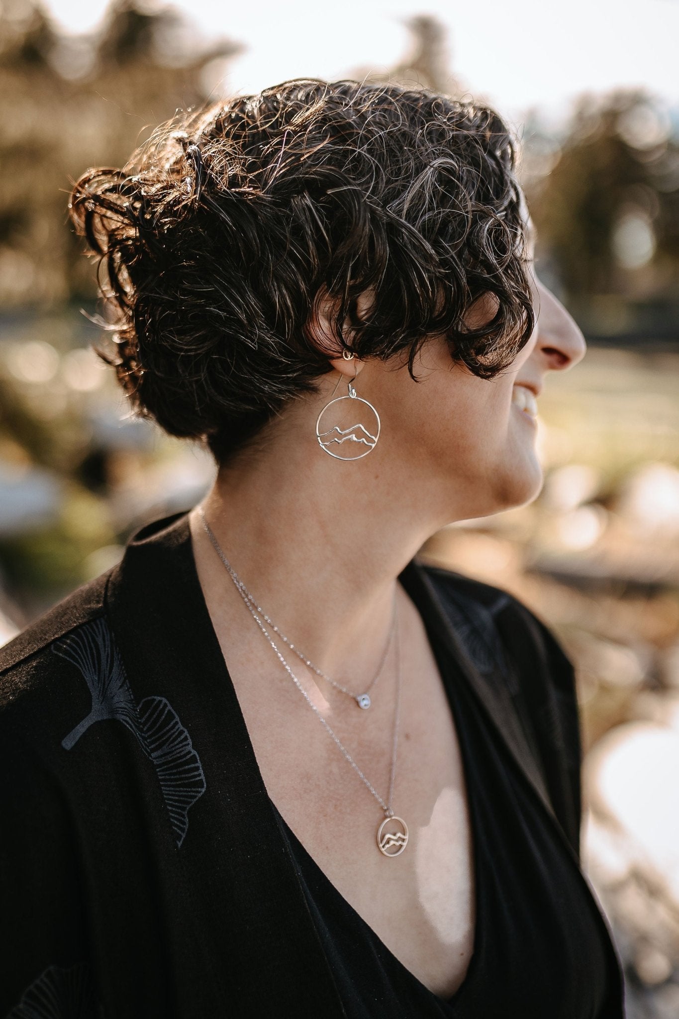 model wearing silver coast mountain circle earrings with matching layered mountain necklaces