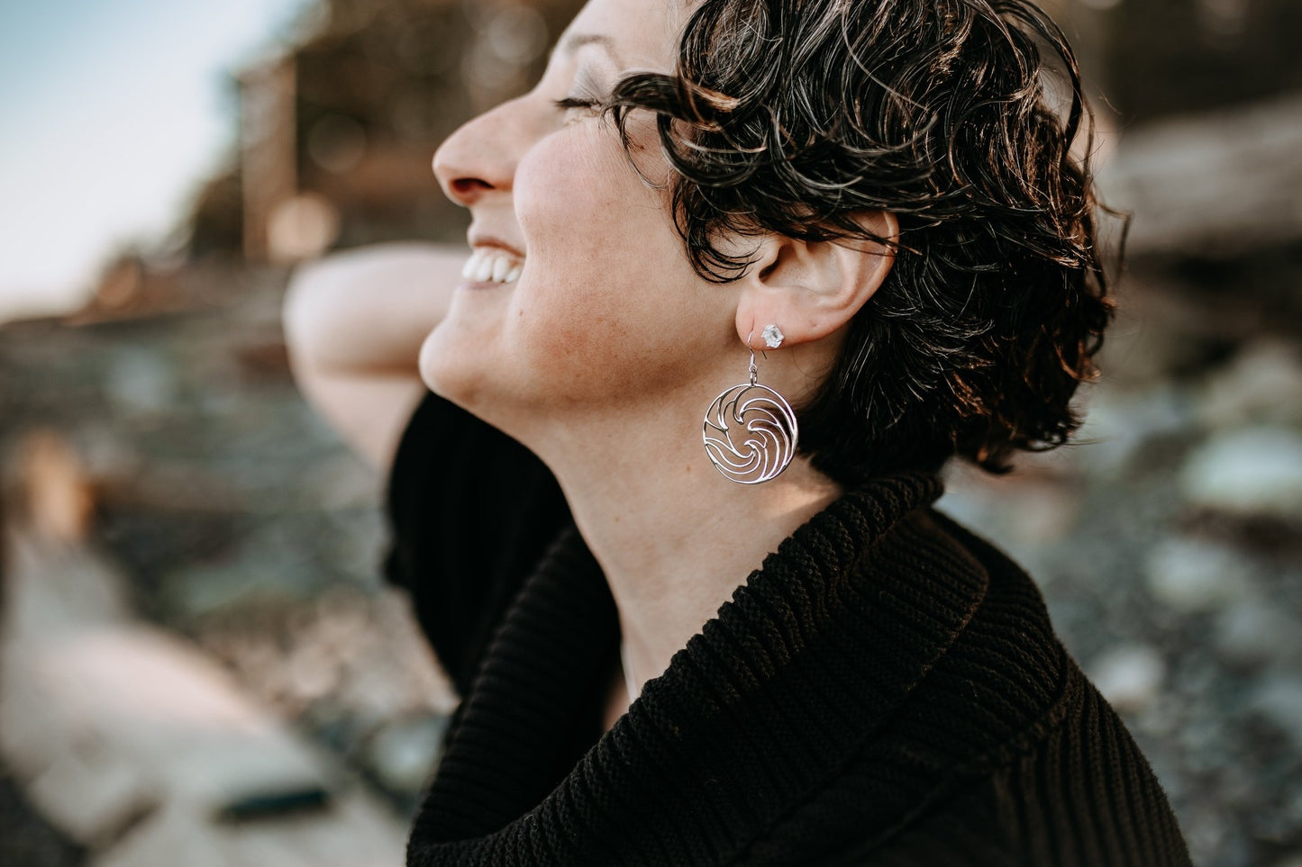 side view of model at beach wearing ocean wave silver circle earrings paired with herkimer diamond stud earrings