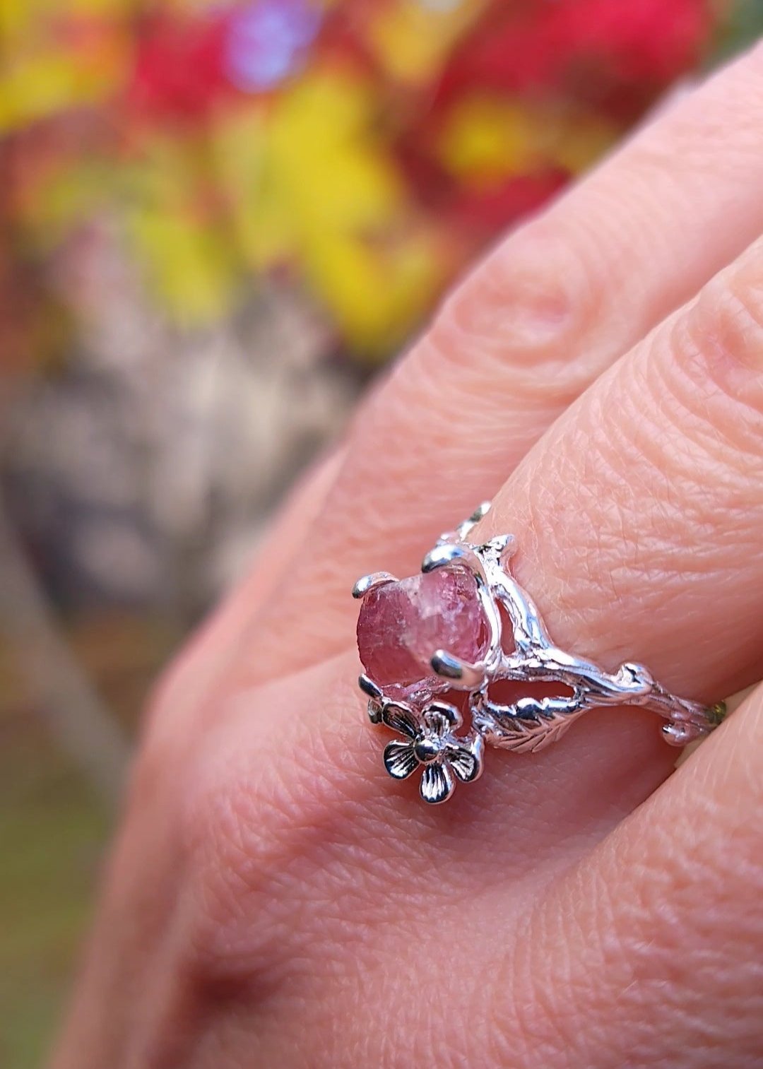 close up of one silver flower leaf and tourmaline ring on hand