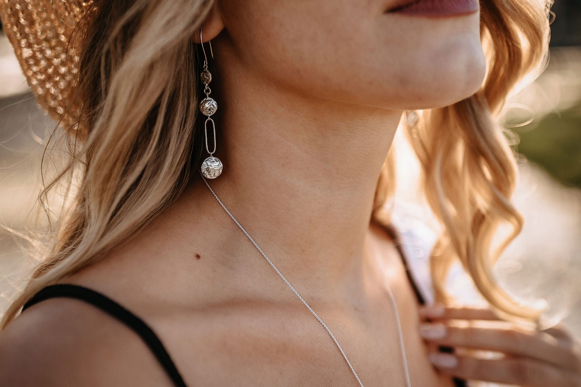 model in straw hat wearing silver driftwood textured lightweight chandelier statement earrings 