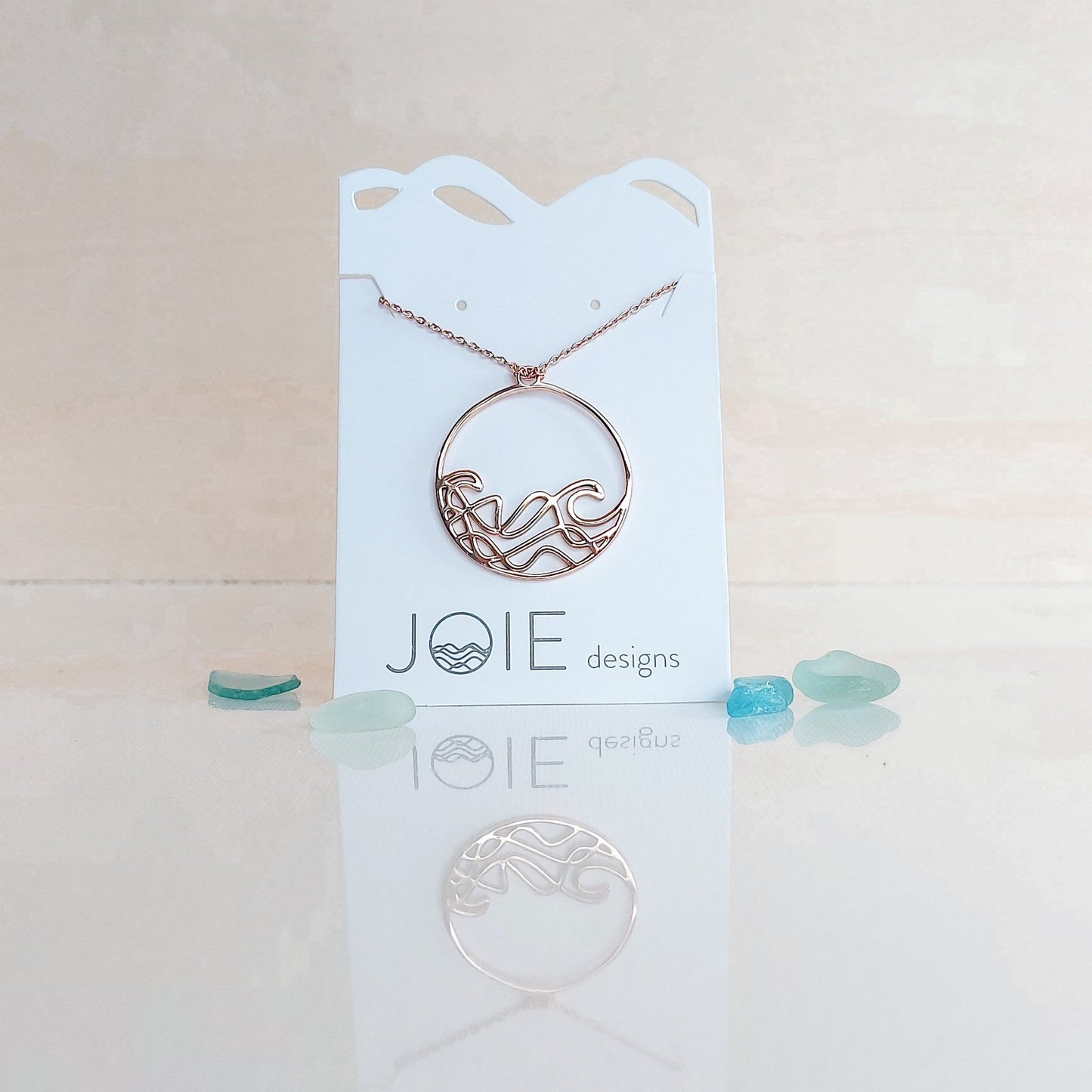 18k plated rose gold round beach wave necklace. surf wave pendant on chain necklace on white jewelry card